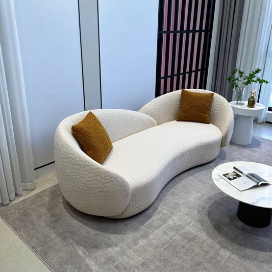 Modern ivory curved sofa with orange pillows in a bright room